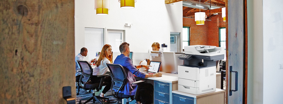 People working in an office next to a Xerox VersaLink BB625 MFP