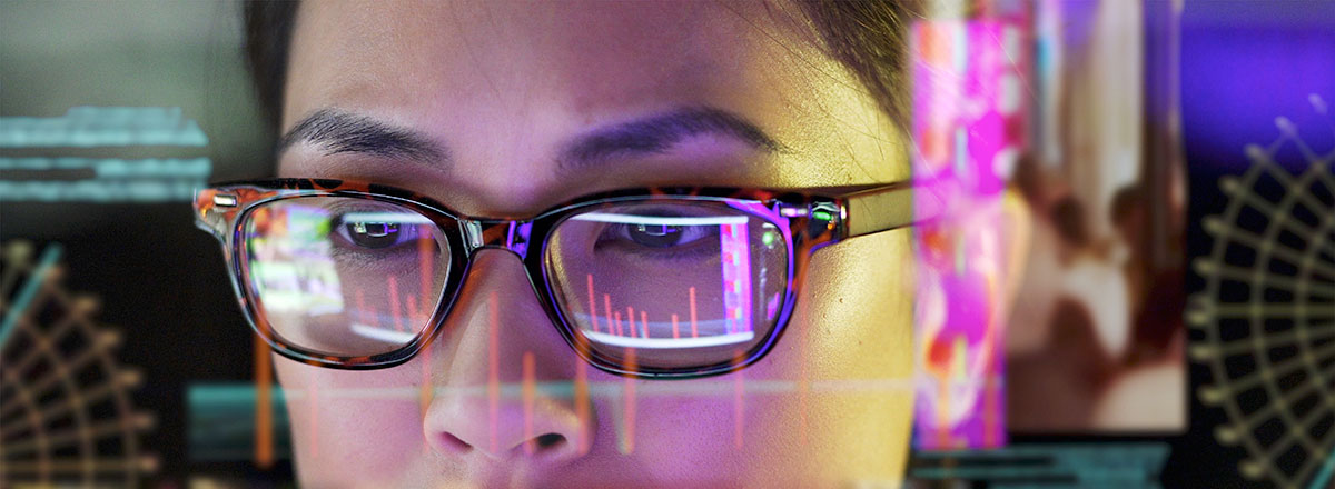 Woman with glasses studying data on a transparent screen