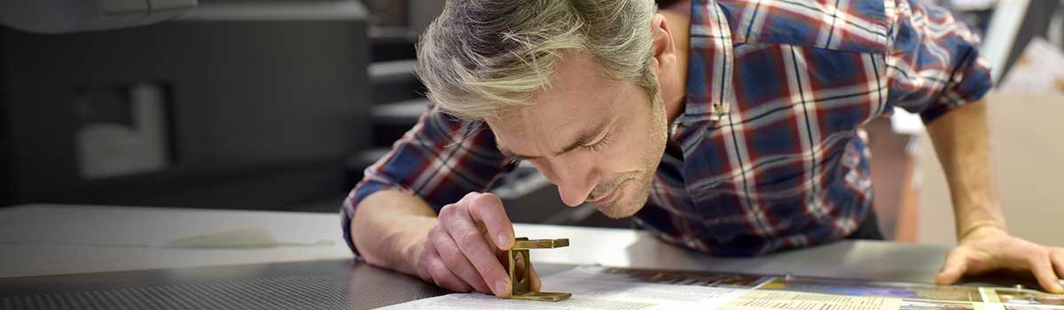 Man using a magnifying glass to examine a print sample