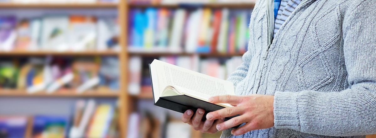 Man in sweater reading a book in a library