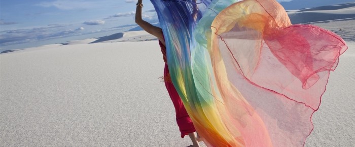 woman running with colorful fabric on the beach