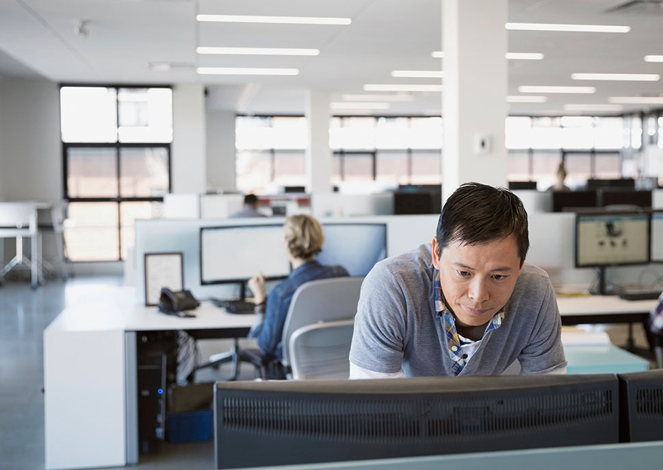 IT professional looking at a computer monitor in a cubicle