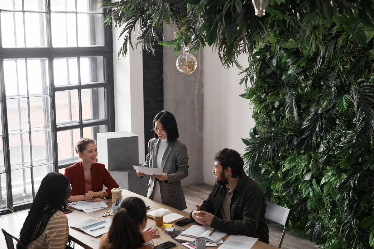 Business people meeting in a room with large windows and a wall of plants