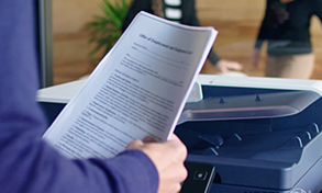 Person holding paper documents over a ConnectKey MFP