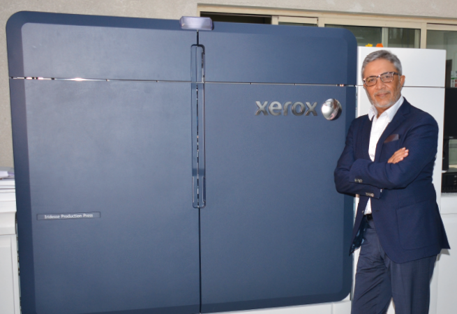 Amit Radia, CEO of Atlas Printing Press, standing next to an Iridesse Production Press. 