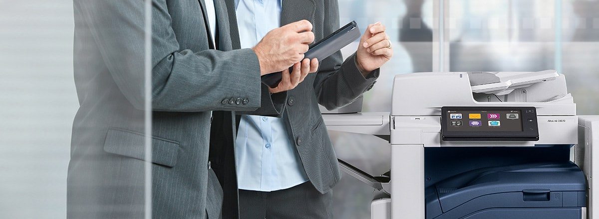 man holding tablet in front of printer