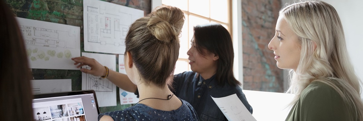 Three women looking at charts on a wall