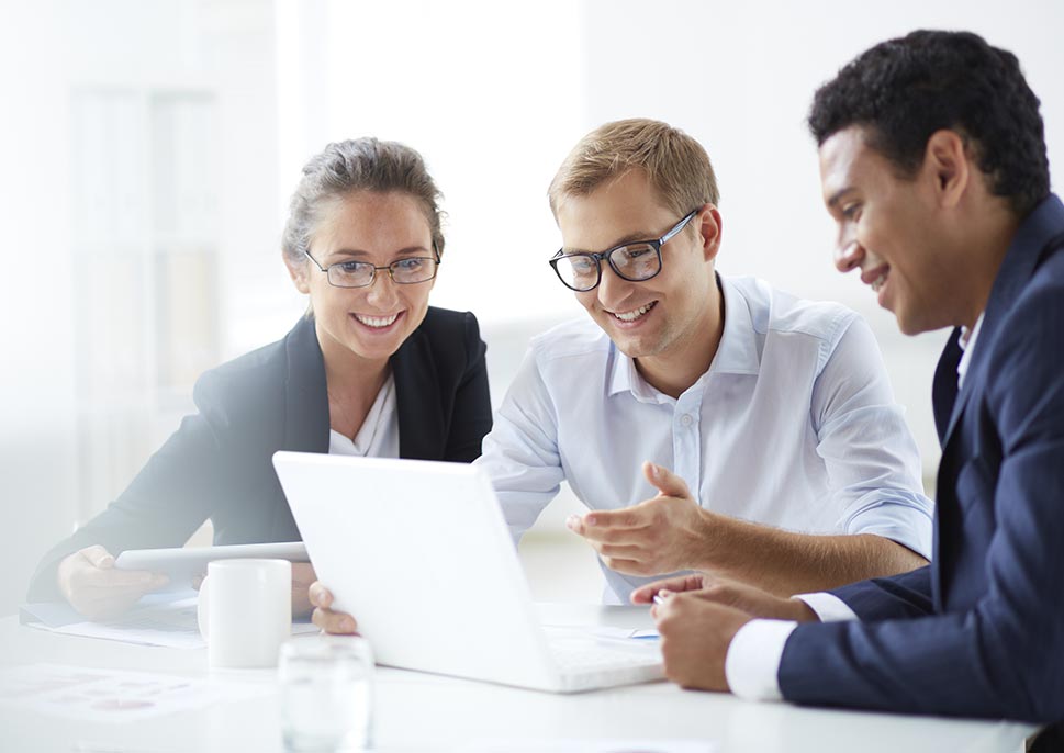 Three people in business clothes looking at a laptop