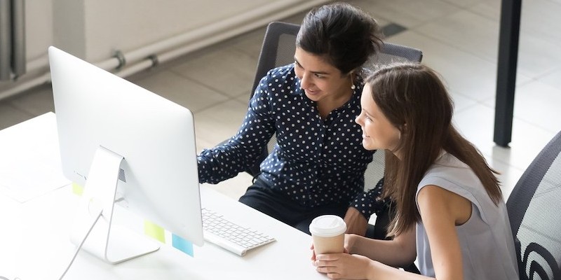 two women sitting together looking at a computer