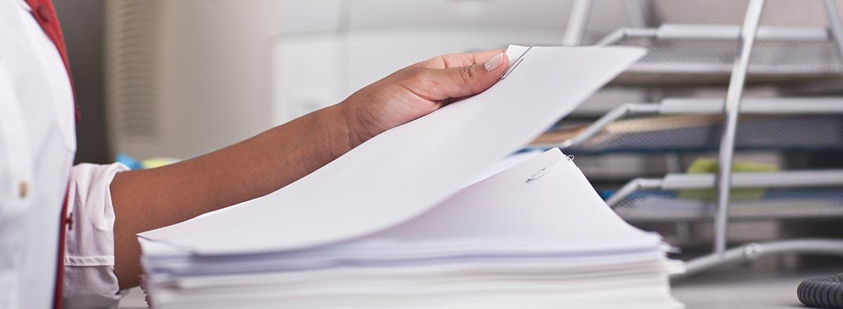 A hand holding a few sheets of paper