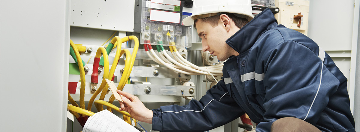 Worker in a construction hard hat checking a series of thick wires