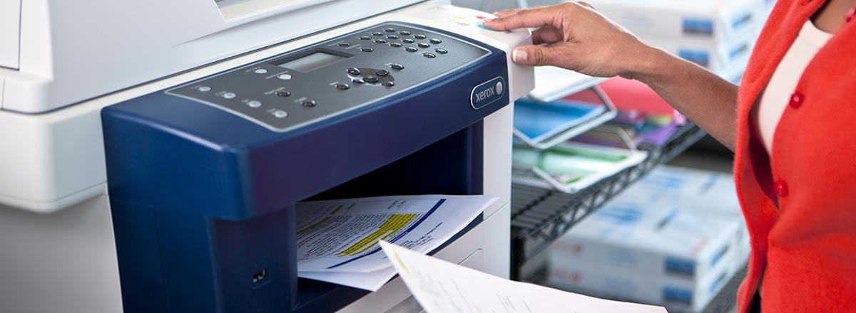 Woman removing prints from an MFP