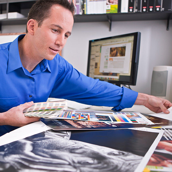 Man in blue shirt examining print samples