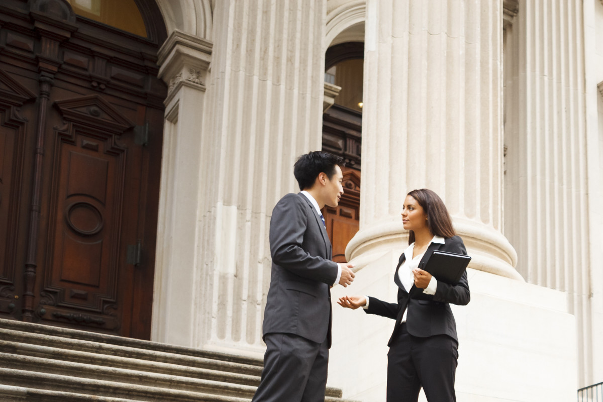 Woman and man in business attire talking on the steps of a government building