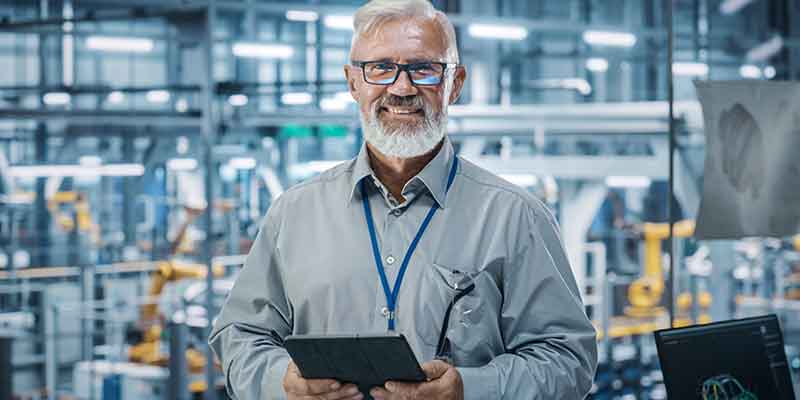 Man with tablet with the interior of a factory in the background