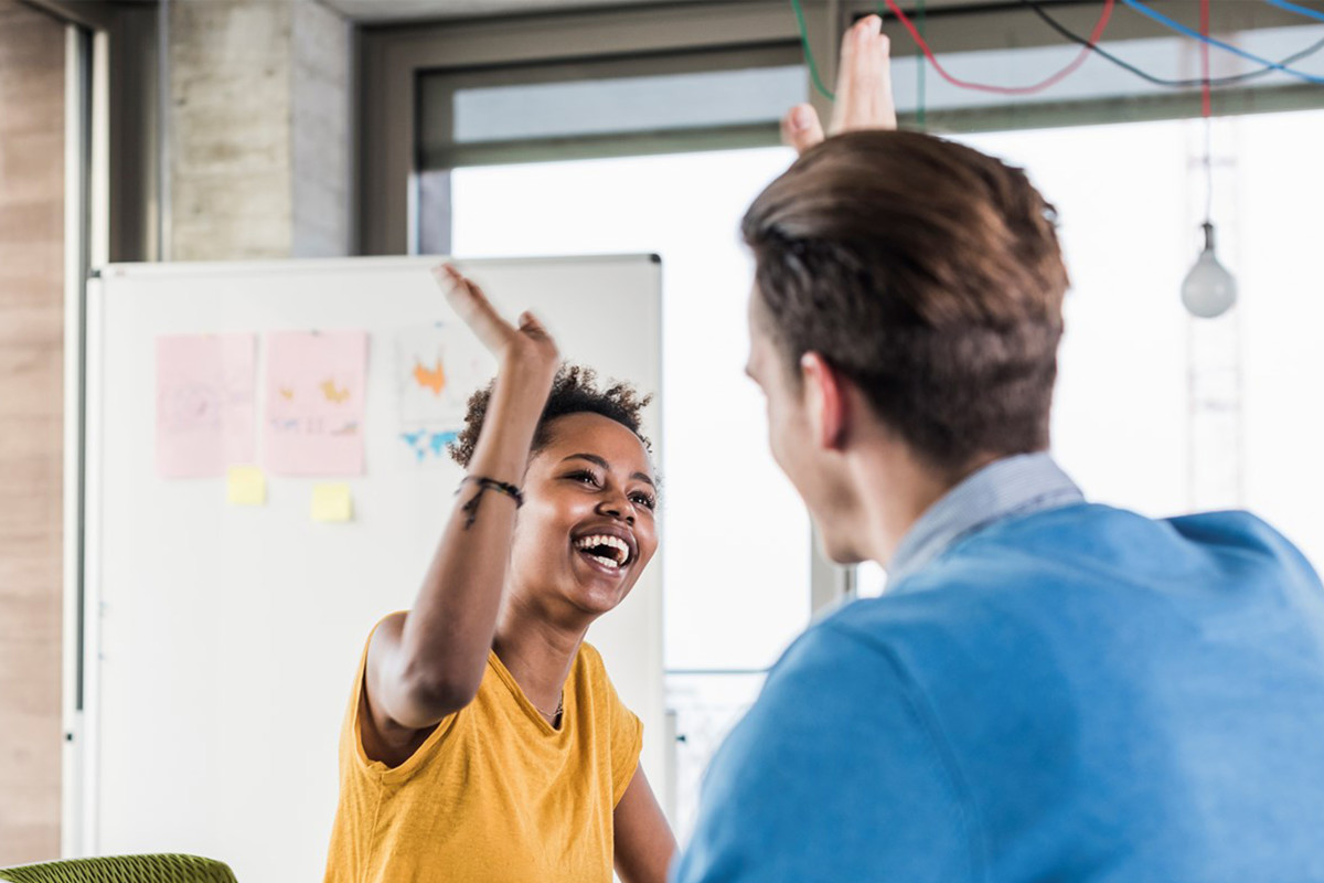 Two employees in front of a whiteboard giving each other a high five