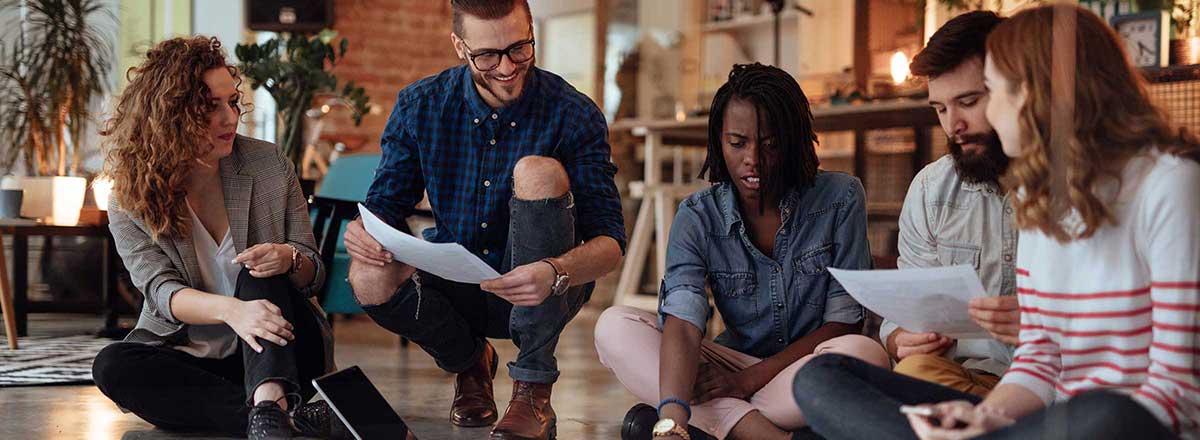 Coworkers sitting on floor reviewing documents