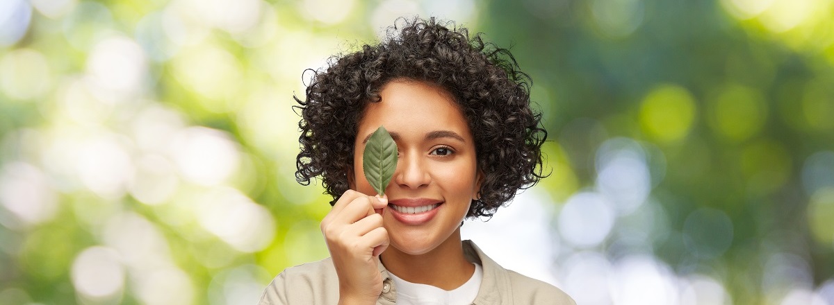 women holding a leaf up to her right eye