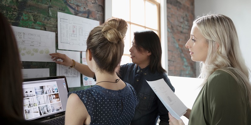 Three women looking at charts on a wall