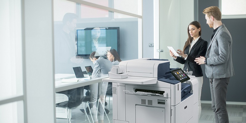 man and woman hovering over a printer