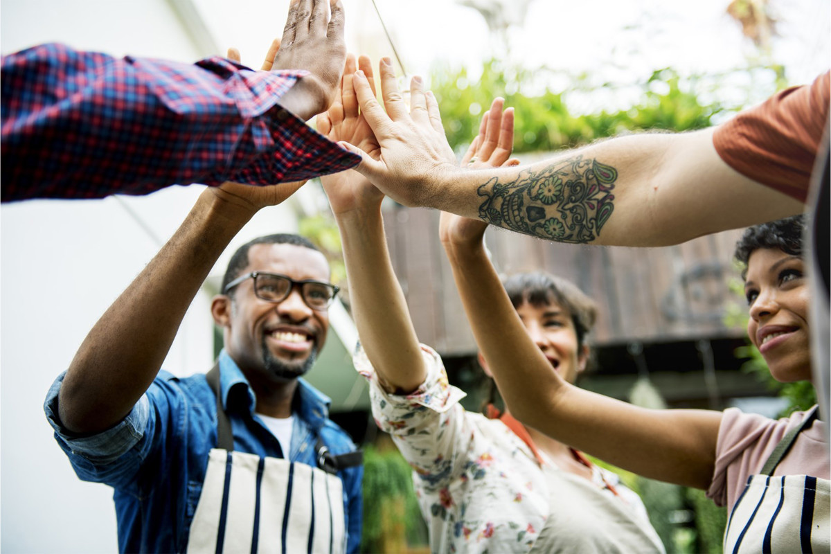 Group of people standing around high fiving.