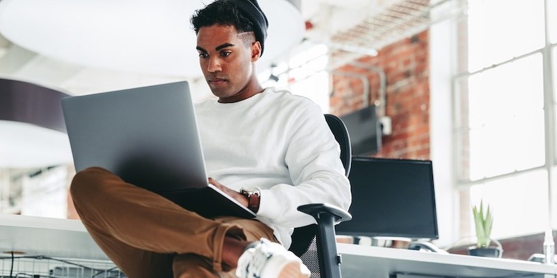 man working on laptop sitting in chair