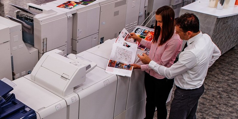 Graphic designers looking at print samples from a Xerox production digital press, with other Xerox digital presses in the background.