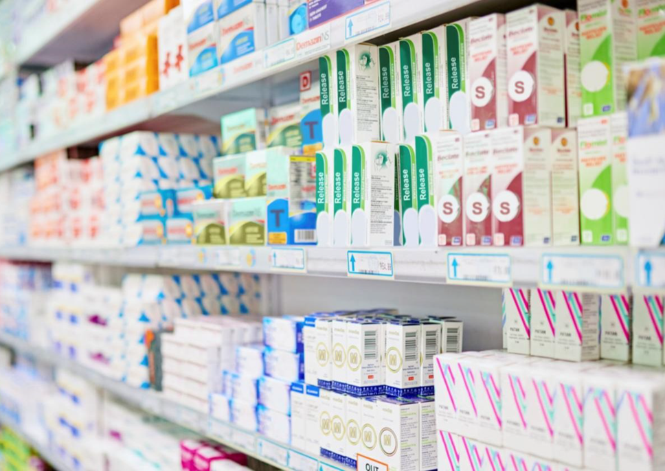 Photo of a pharmacy shelf with numerous different medicine cartons visible