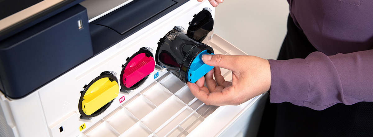 A hand loading a cyan toner cartridge into a Xerox printer