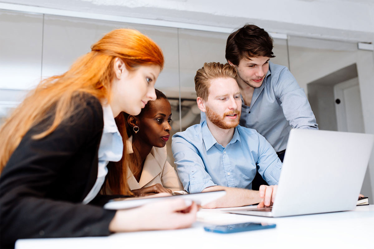 Four colleagues looking at a laptop together