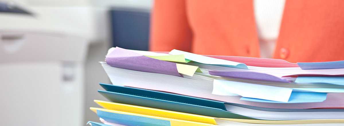 Person carrying a stack of papers in colorful folders
