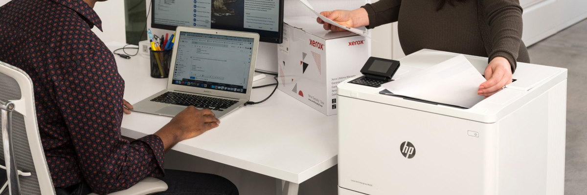 Scene showing a HP printer being used with a Xerox supplies box on the table next to it