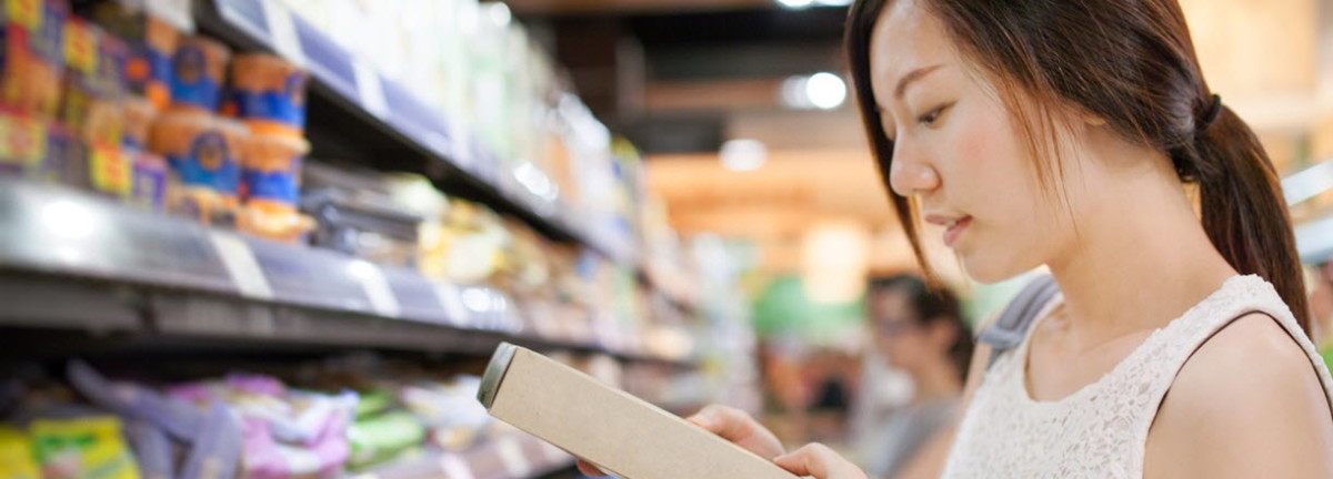 Woman in a store aisle looking at a printed box