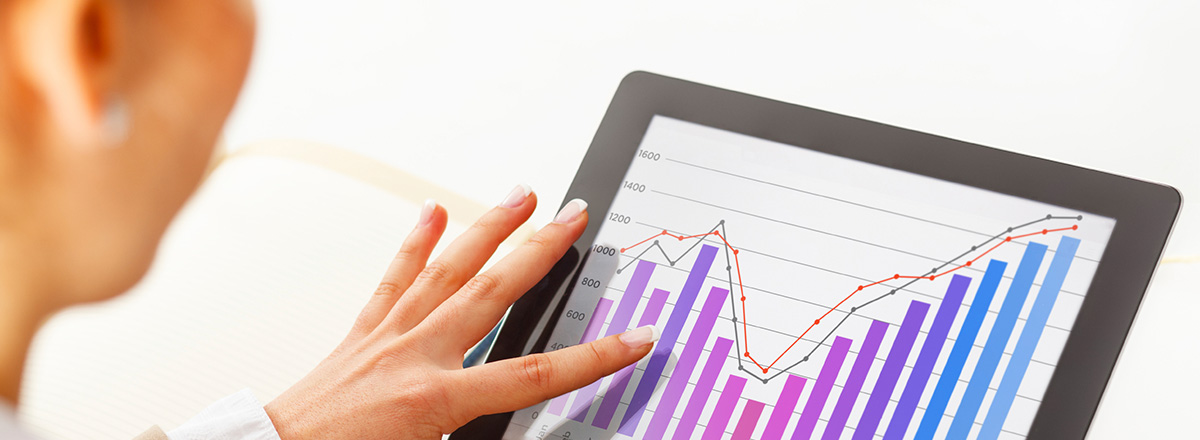 A woman's hand using a tablet that shows a graph on the screen