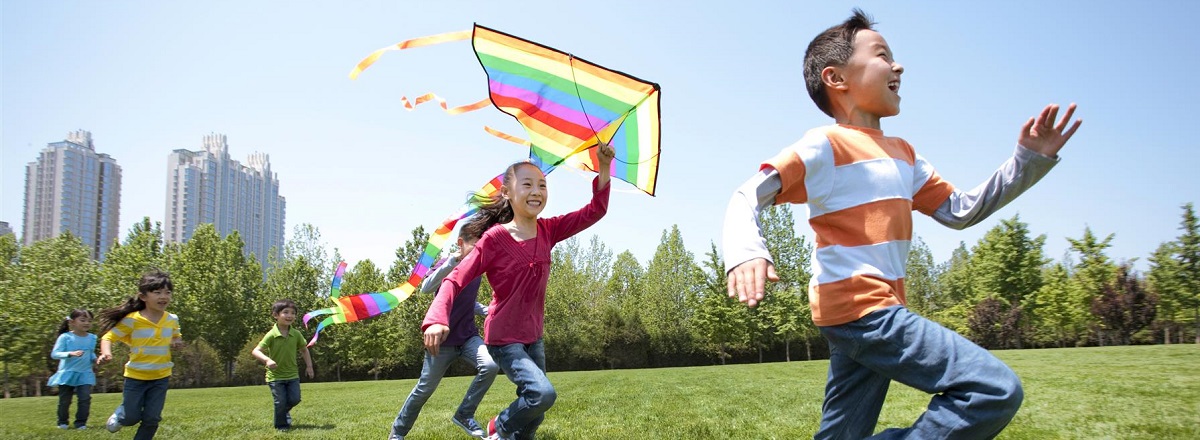 Children in a city park running with a kite
