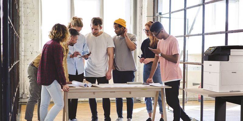 group of people standing over a table working on a project