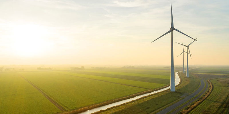 Windmills along a river and green farm fields