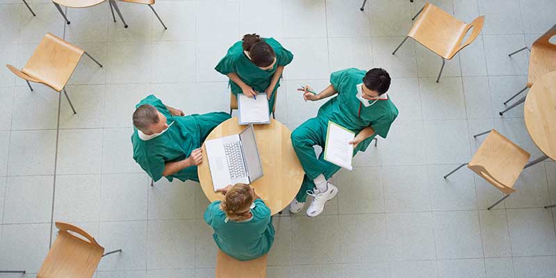 Overhead view of 4 doctors meeting at a small table