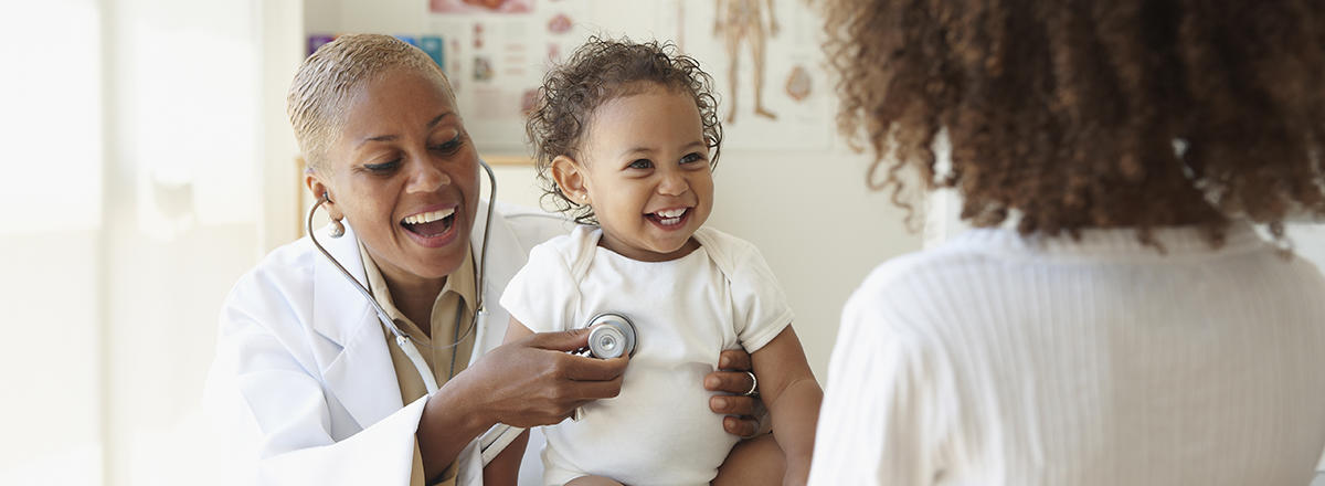 Doctor listening to a baby's heartbeat with a stethoscope. Both are smiling happily.