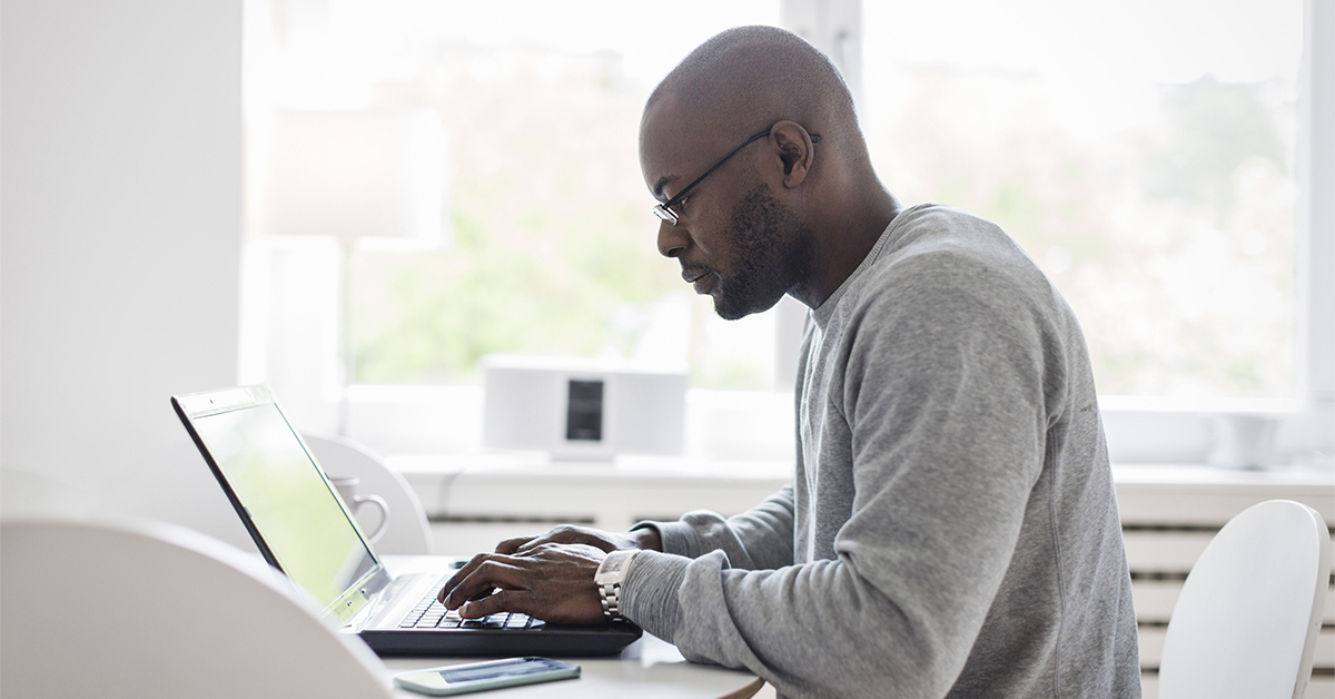 Man working at home using laptop near the big window. Remote work, online  job, work from home. Stock Photo