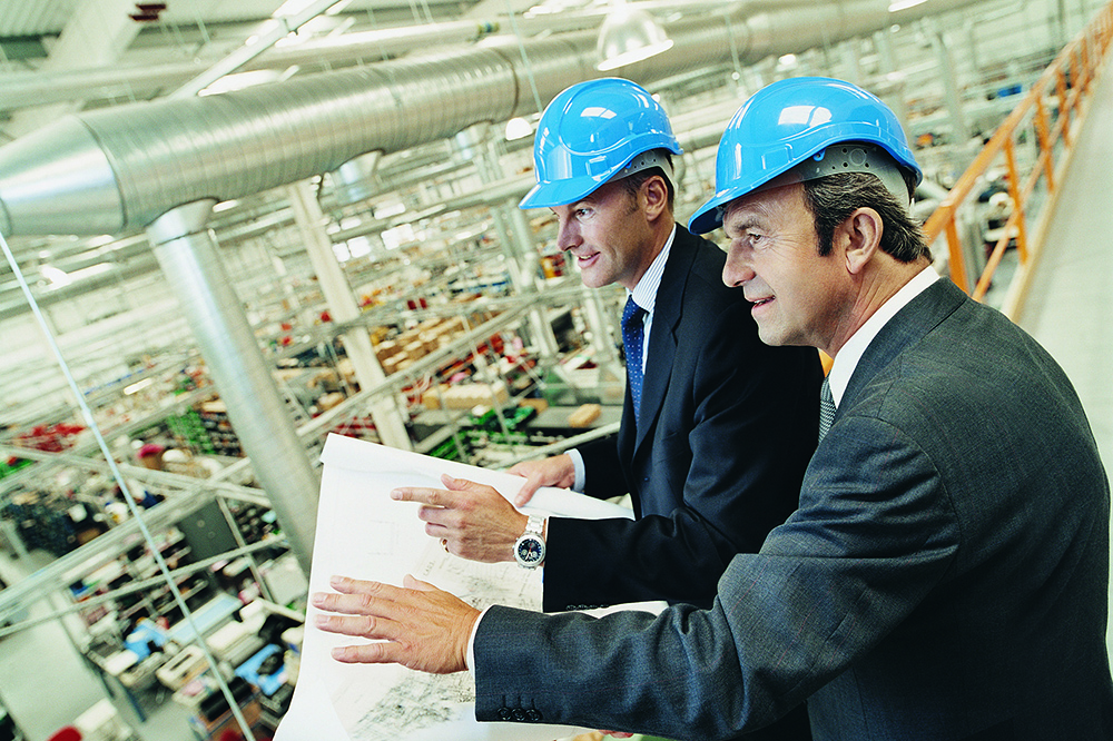 Men in hats looking at large building plans