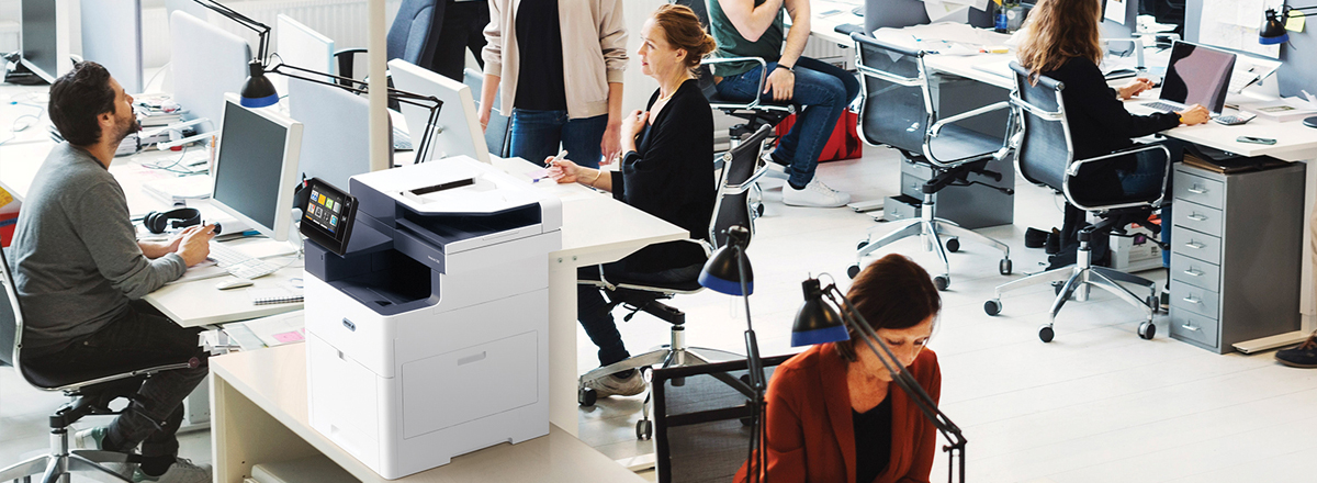 Employees at desks in a busy office, with a Xerox MFP