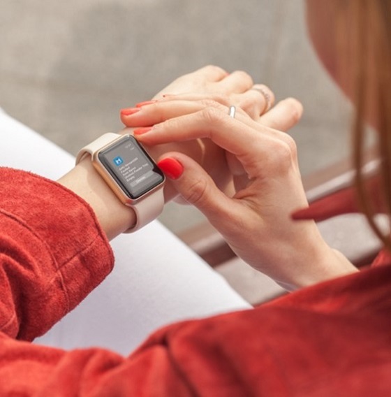 Person in a red suede jacket with red fingernails, looking at a smart watch