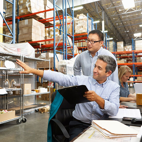 business people in warehouse manufacturing reviewing tablet
