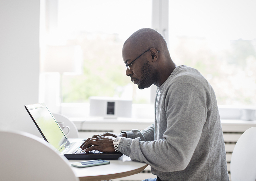 Man working on laptop in room with servers in the background.