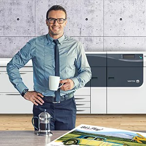 Man with coffee, standing in front of a Xerox digital press, with a colorful print sample in front of him
