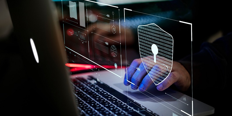 Fingers typing on a laptop keyboard, behind a transparent row of security icons