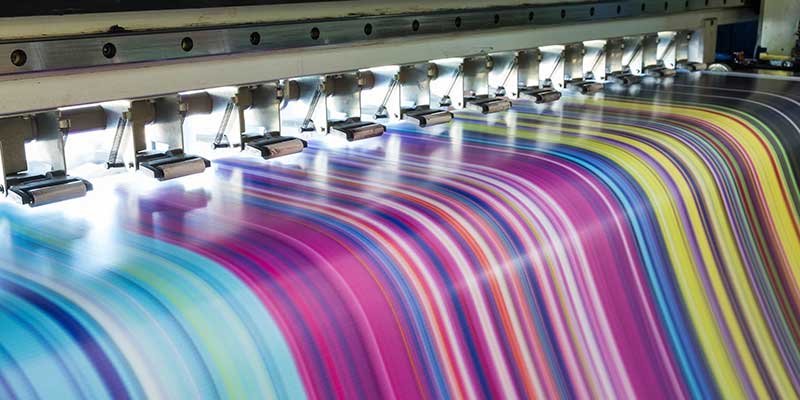 A colorful print exiting a production printing device