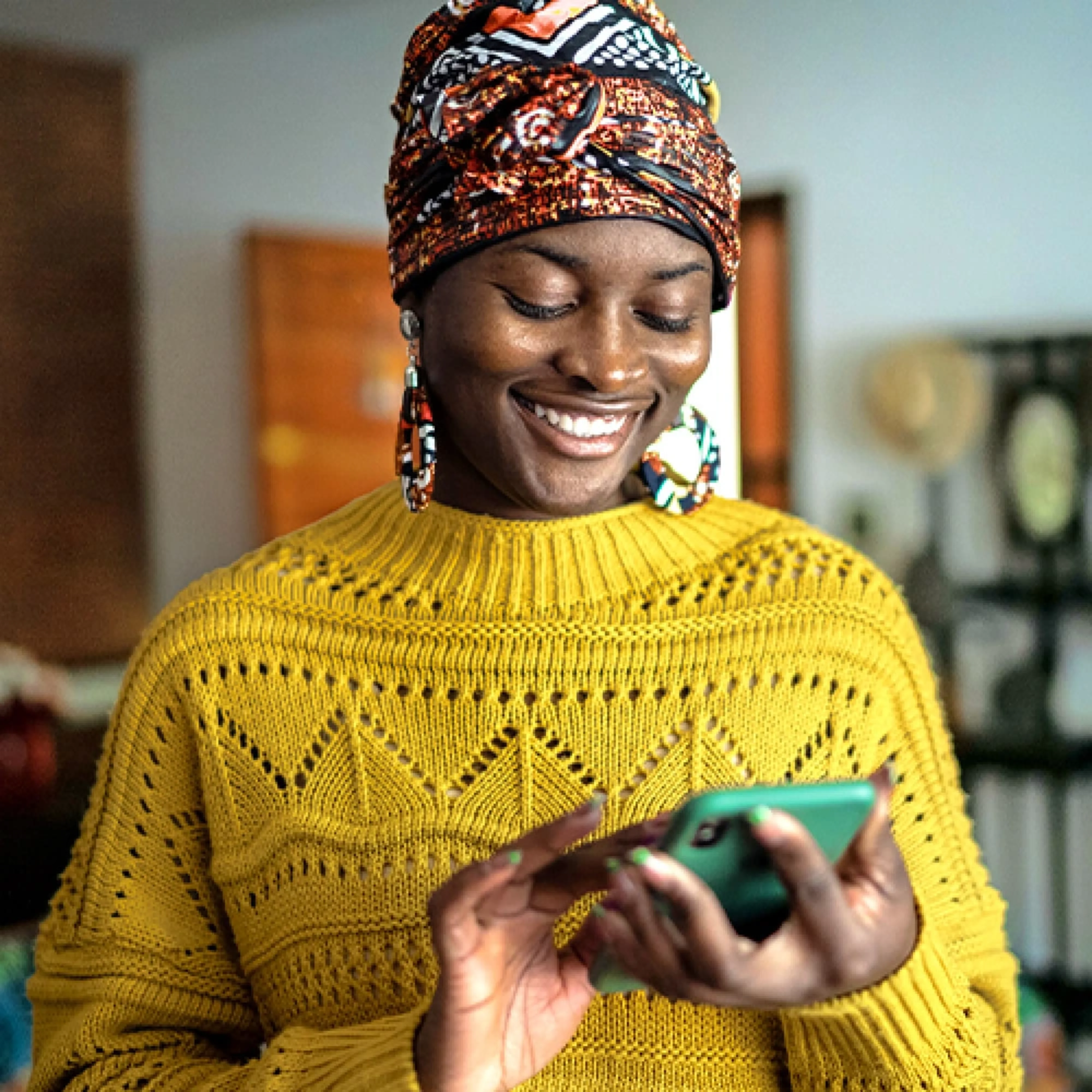 Smiling person in a yellow sweater enjoying mobile banking on their phone.
