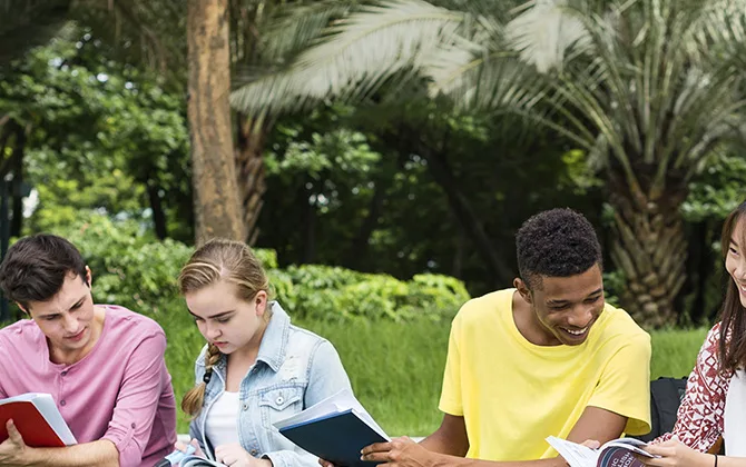 Teenagers sitting in the park while reading books